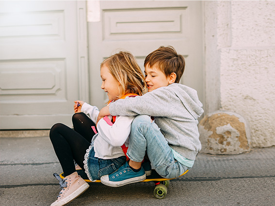 Niño y Niña jugando con el monopatín.